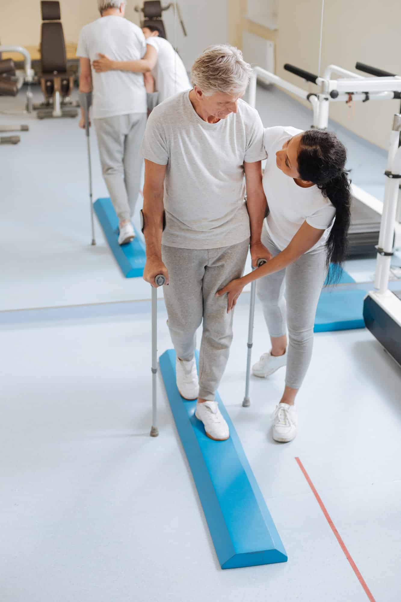 A man with crutches and a woman with crutches in a gym.
