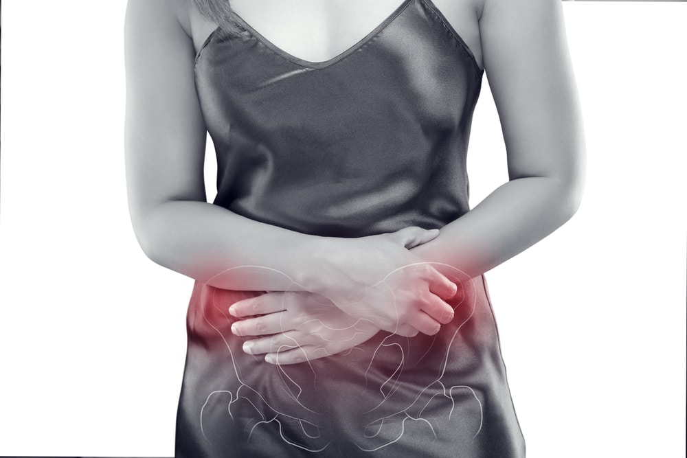 A woman is holding her stomach in pain.