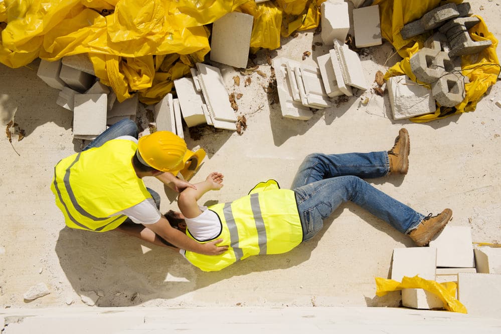 Two construction workers laying on the ground.