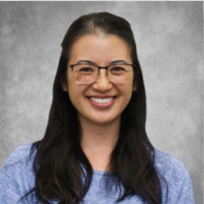 A woman in glasses is smiling for the camera.