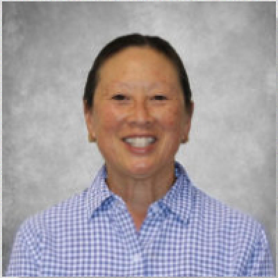 A smiling woman wearing a blue and white checkered shirt.