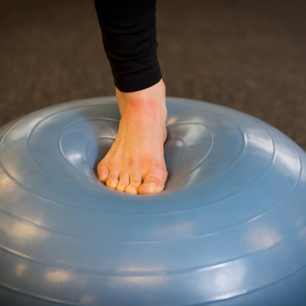 A person's foot on a blue exercise ball.