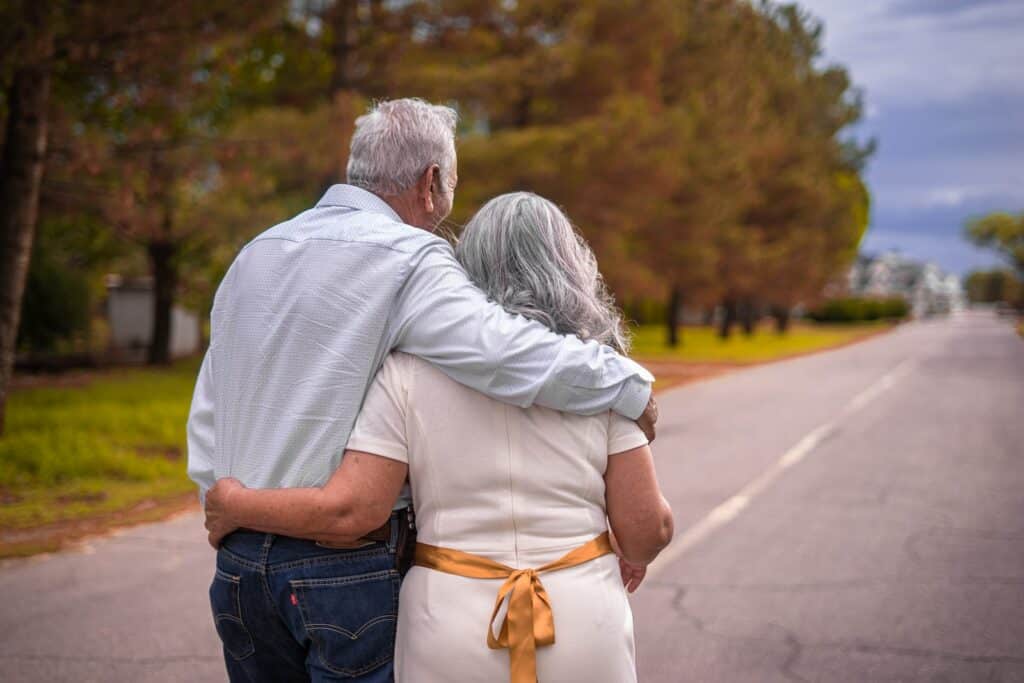 An elderly couple walking down a road.