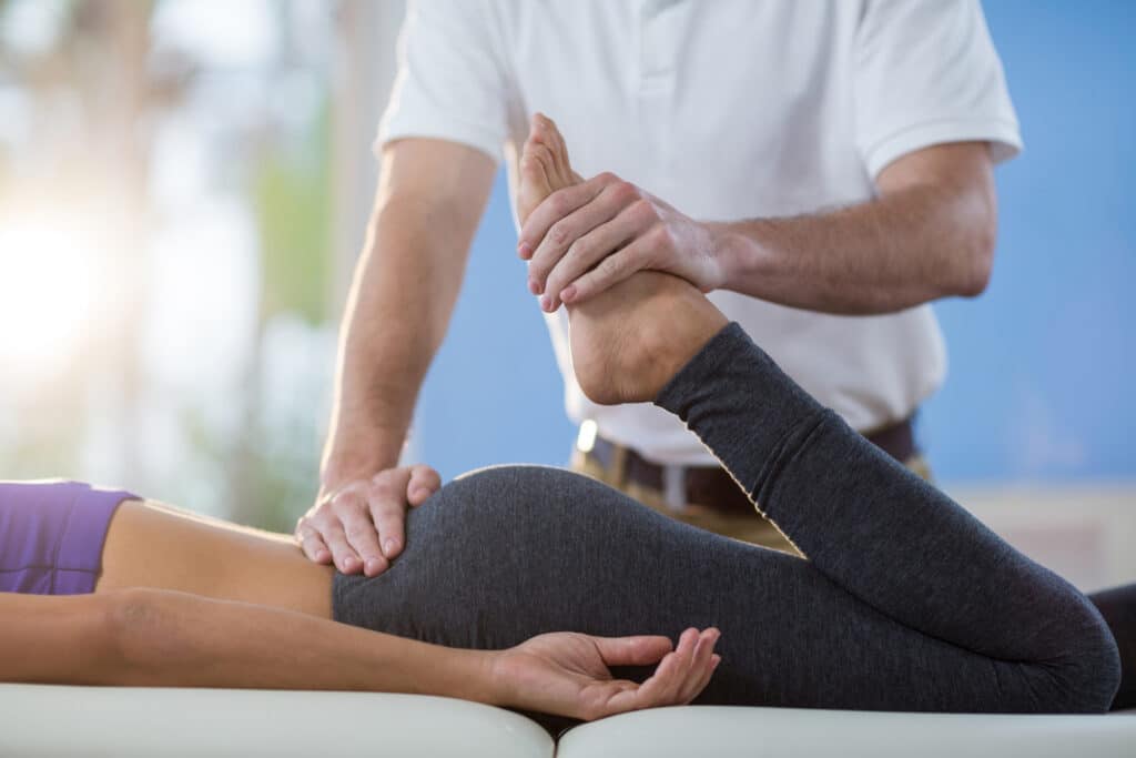 A woman is having her leg massaged by a physical therapist.