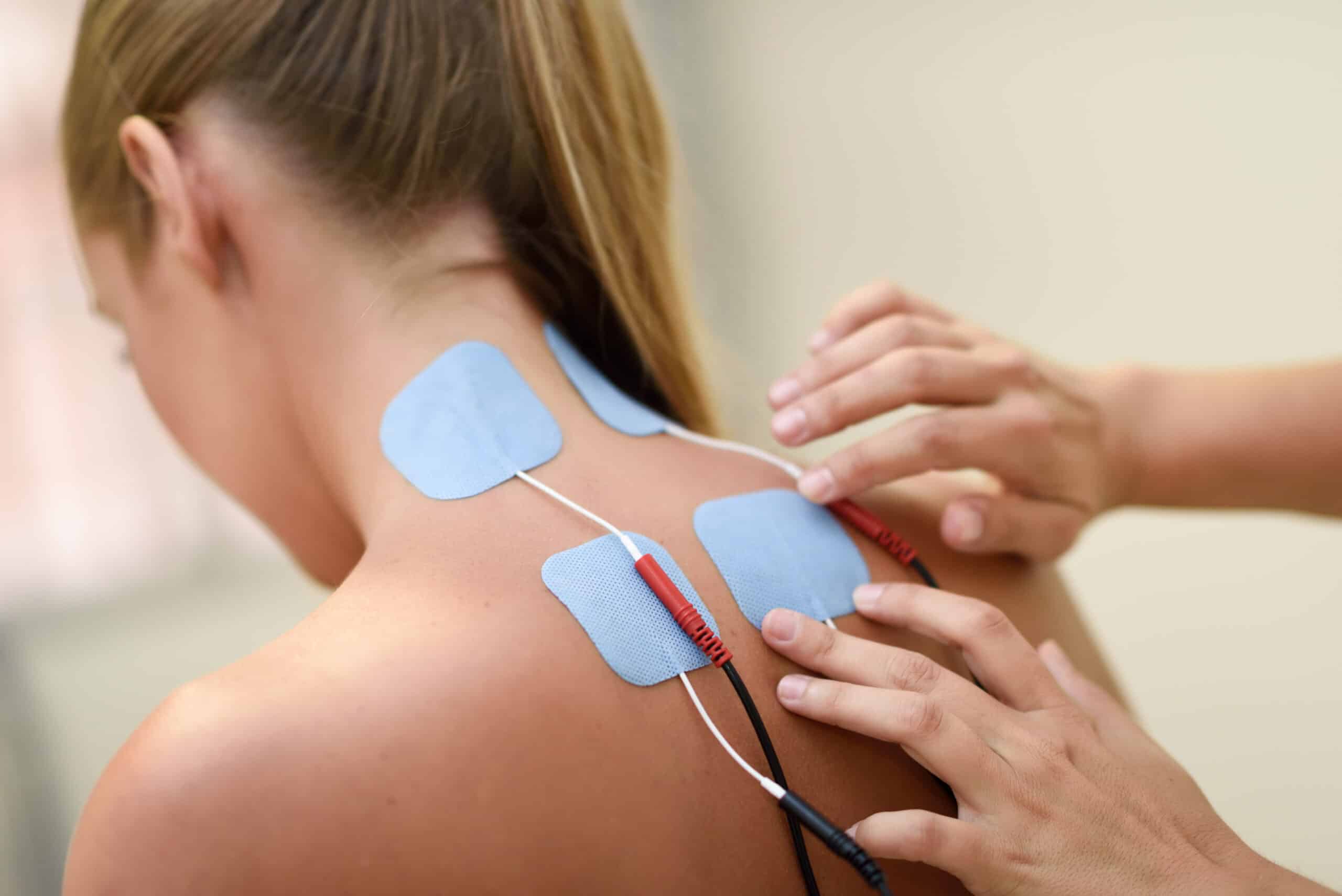 A woman is getting an electrical treatment on her back.