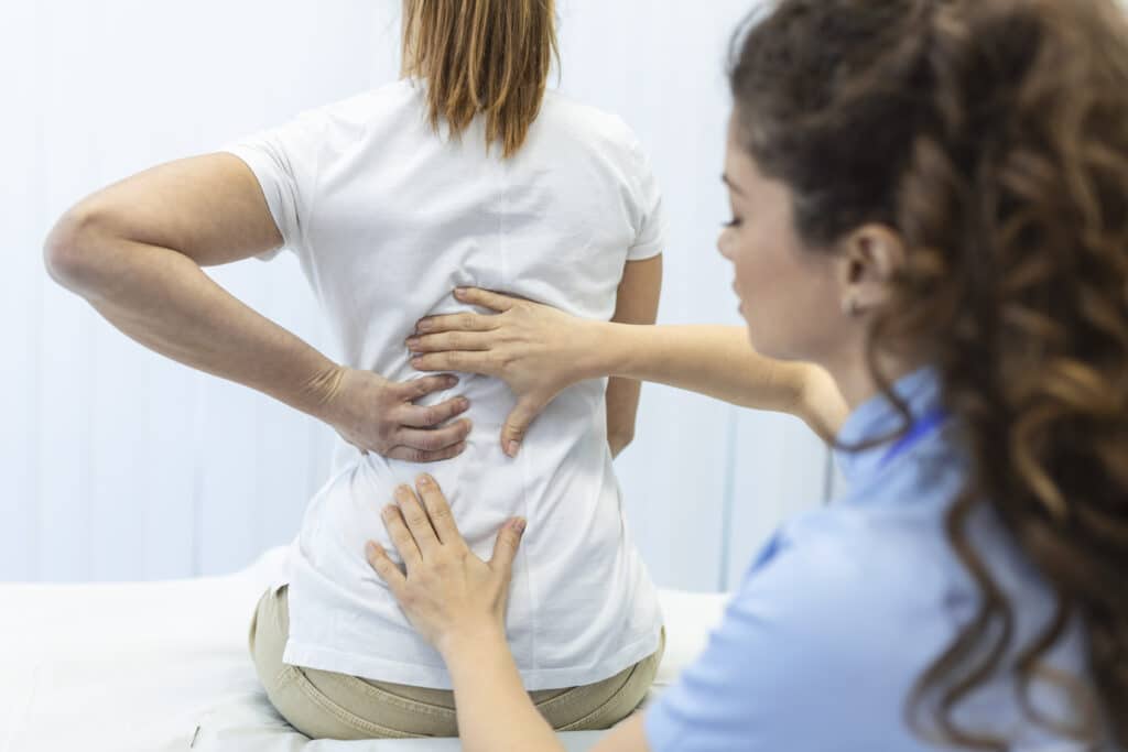 A woman is having her back examined by a doctor.